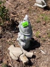 Plastic gnome, carrying a candle with a concrete bird statue beside it